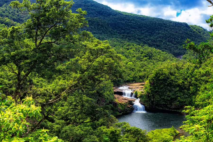 The could be a photo from any travel brochure offering tropical paradise. There's lush green scenery with a rive cutting through it. The river has a waterfall that could be used in shampoo commercials.