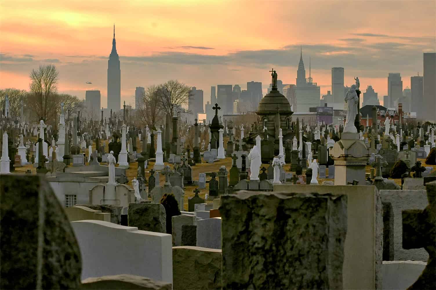Cementerio del Calvario, Queens, Nueva York. Los monumentos verticales del cementerio se hacen eco de los verticales de los rascacielos de Manhattan al fondo.