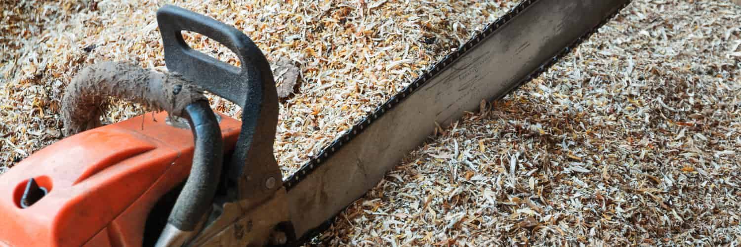 A photo of a chainsaw in a pile of sawdust.