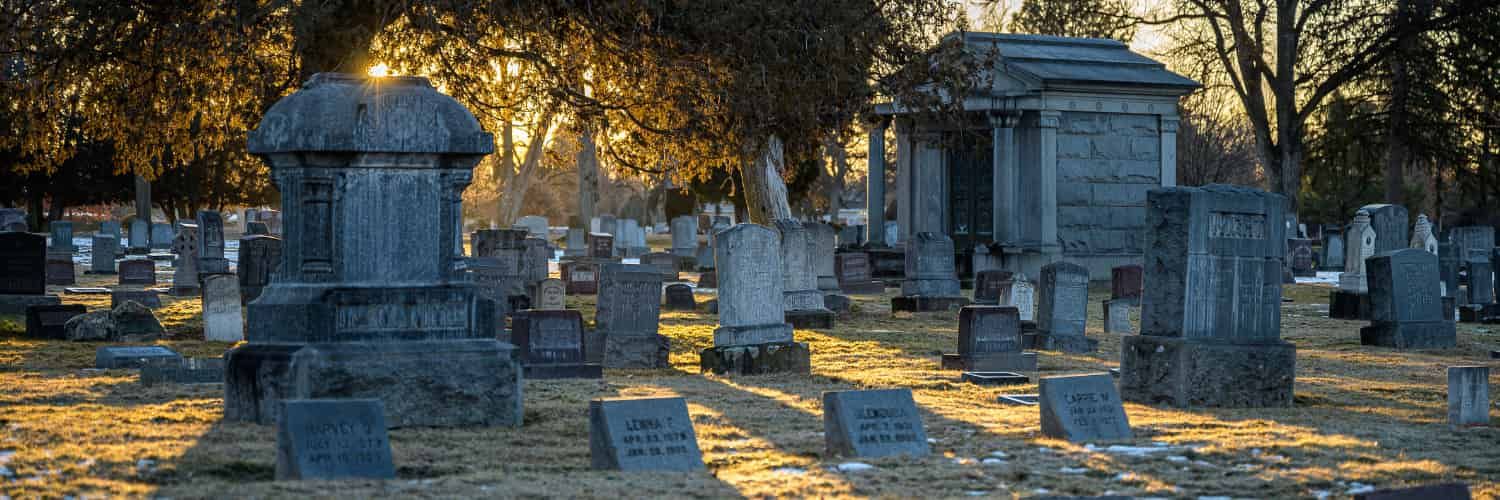Shadows fall across a cemetery as the sun sets.