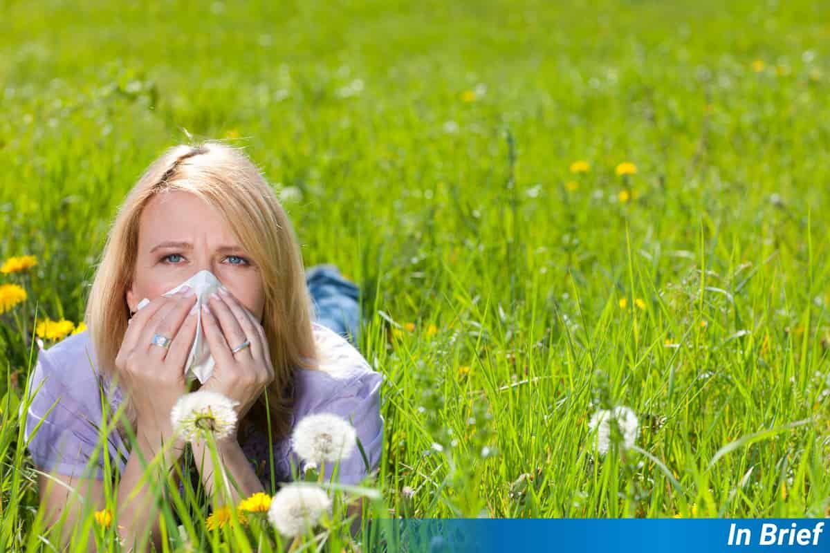 A woman suffering from hayfever in a park.