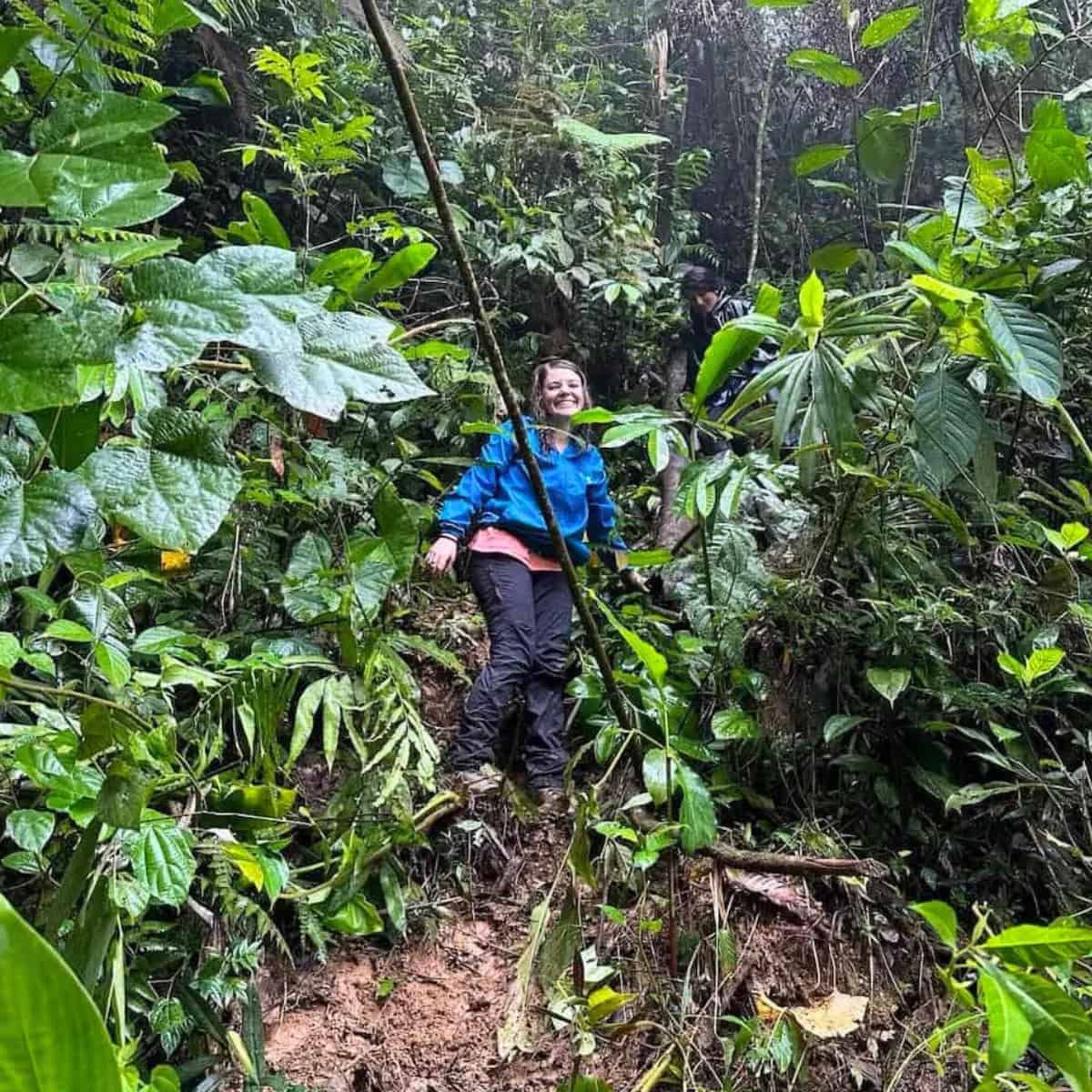 A woman, smiling, in the midst of the rain forest.