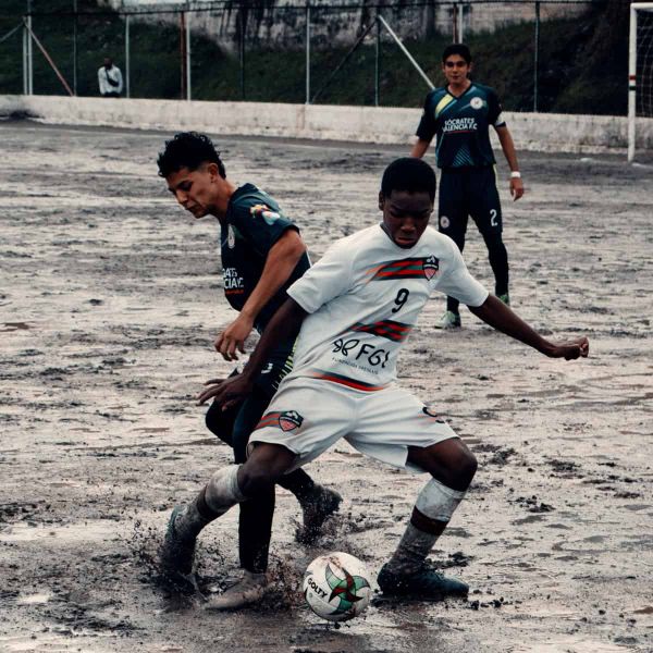 Kids playing football on a muddy pitch in Colombia
