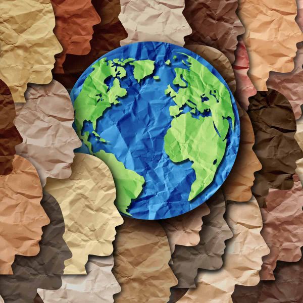 A series of paper cut outs of heads in various shades, signifying diversity. Among them is the planet Earth.