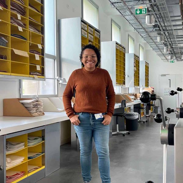 Gláucia Silva standing smiling in a herbarium.