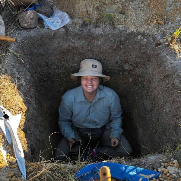 A woman in a pit smiling up at the camera.