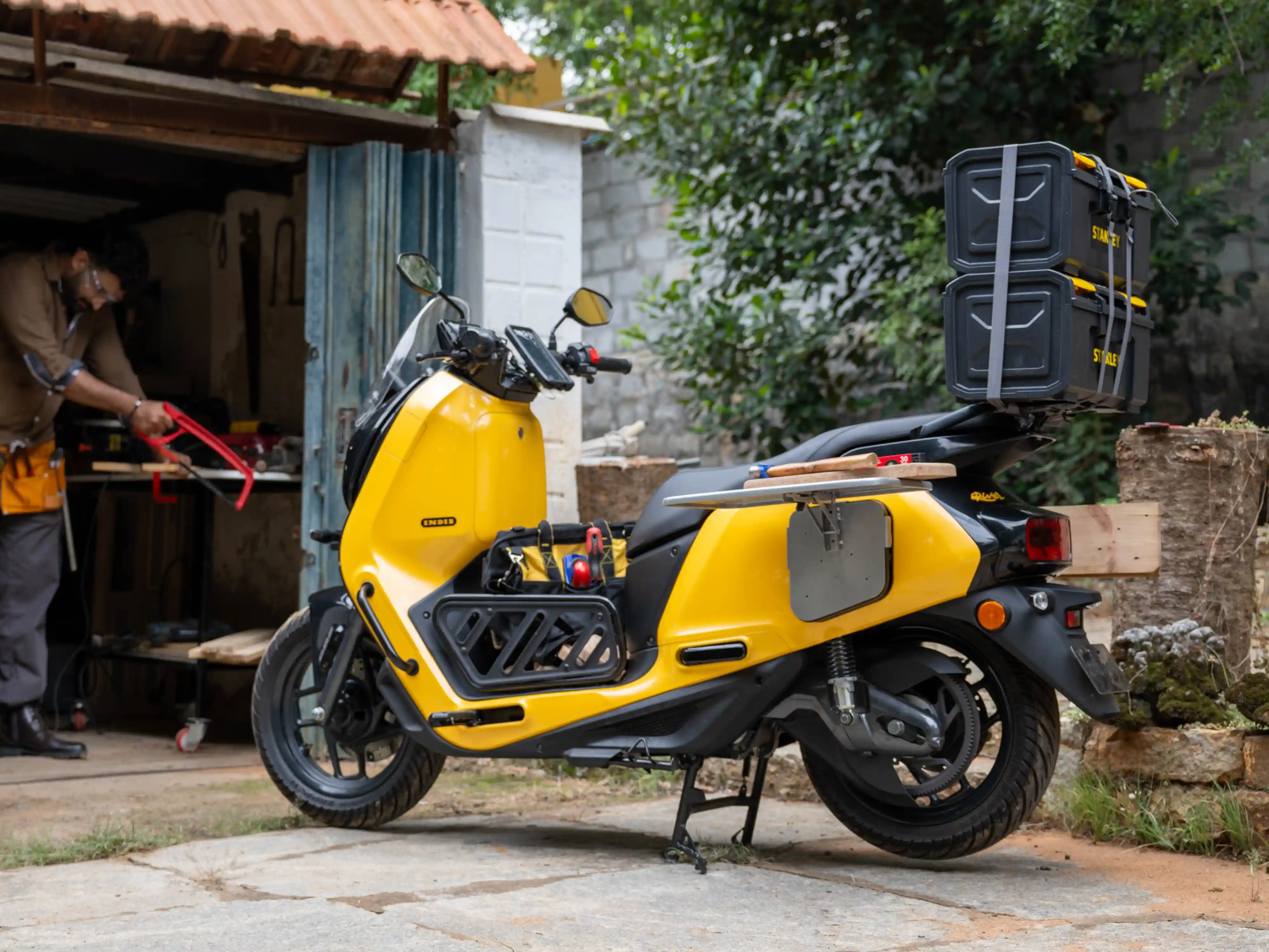 Yellow River Indie electric scooter modified into a mobile carpenter workshop with floorcage, top-boxes, and a side table.