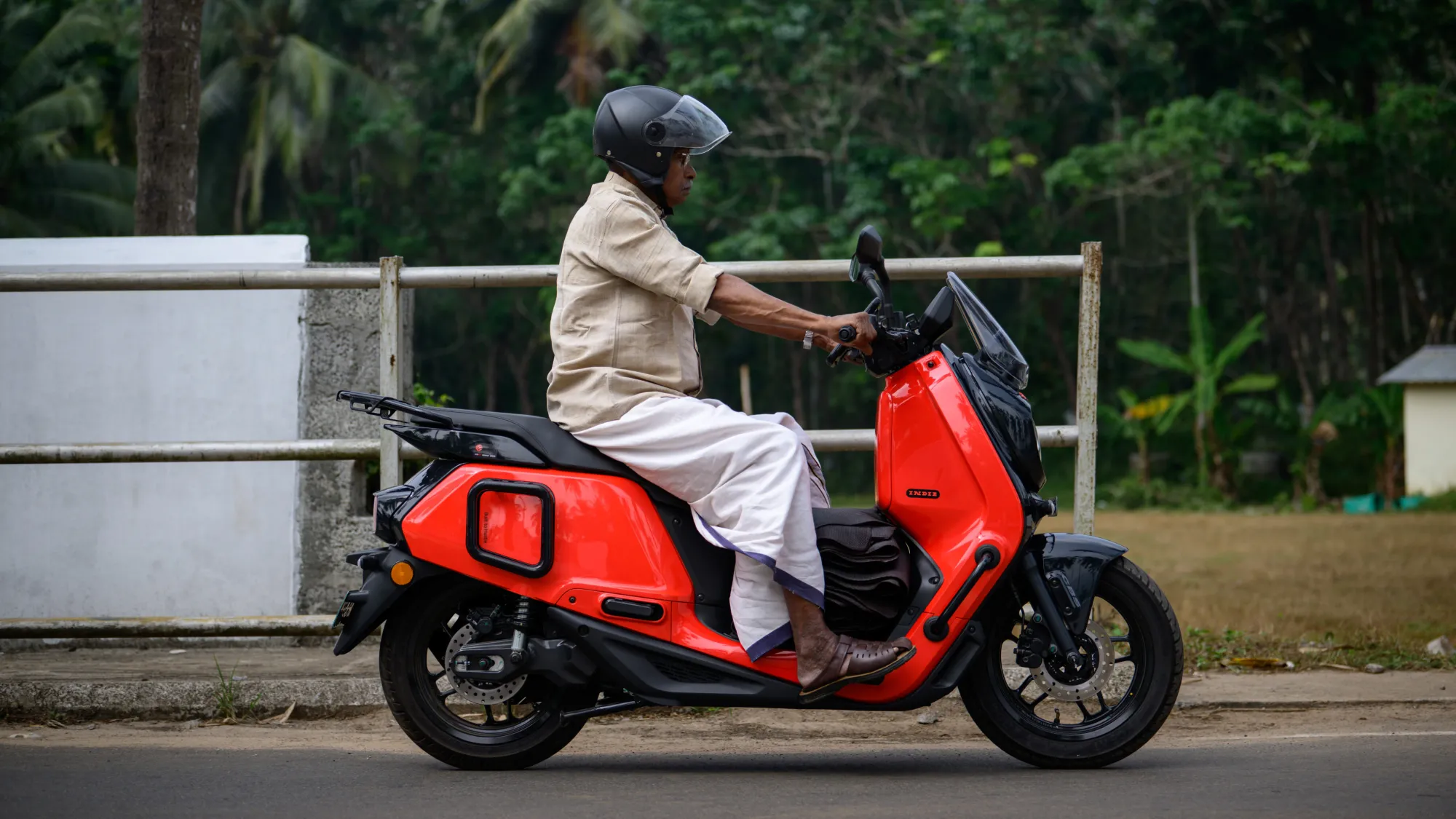 Farmer riding Indie using front foot-pegs; solving legroom problem and safely carting rubber sheets