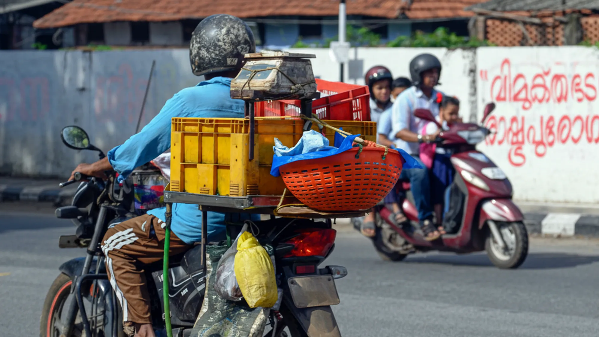 Motorcycle pillion seat and carrier modified with crates and a weighing scale for vending; example of Indian jugaad.