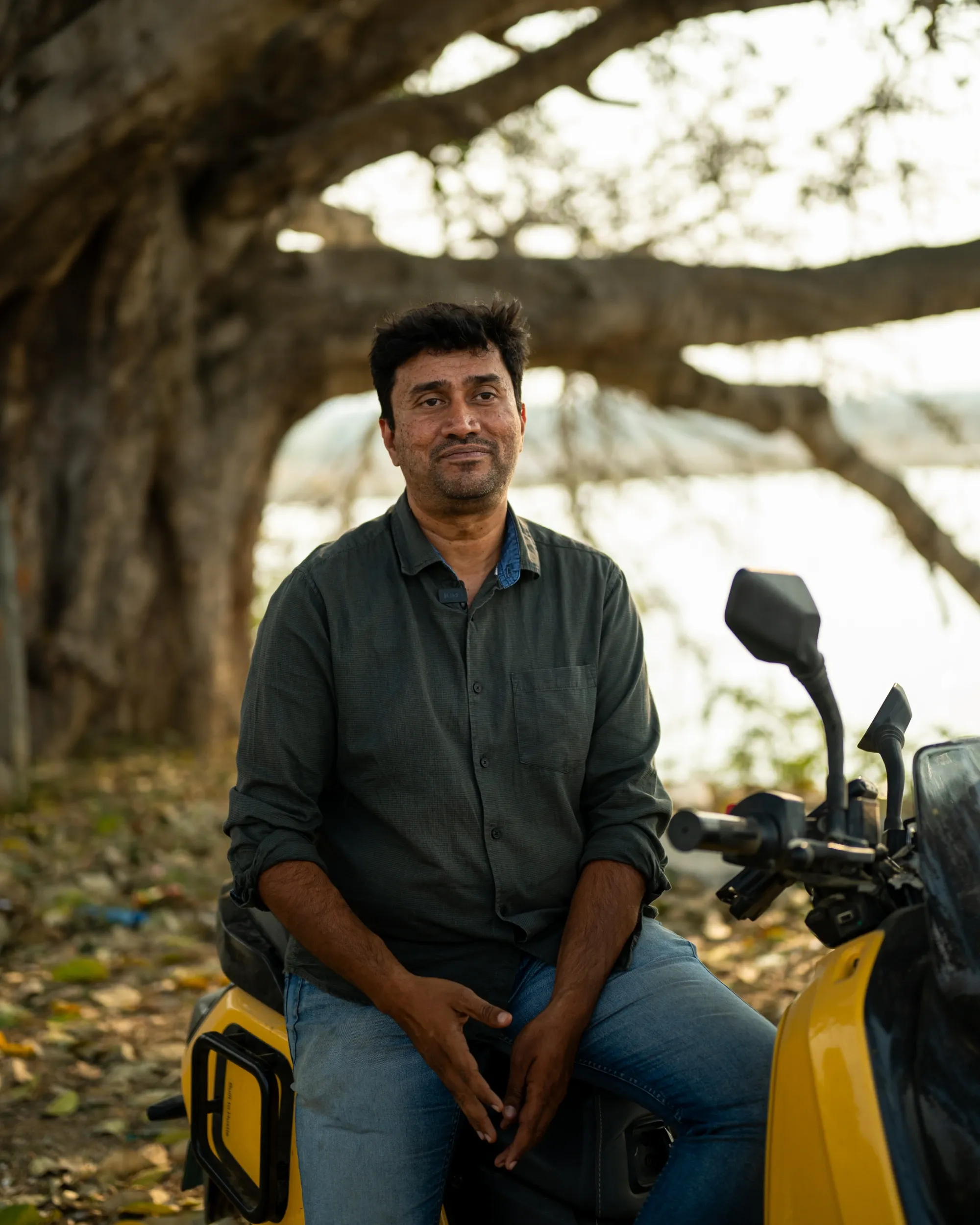 Ramakrishna sitting on Spring Yellow Indie, parked under a tree