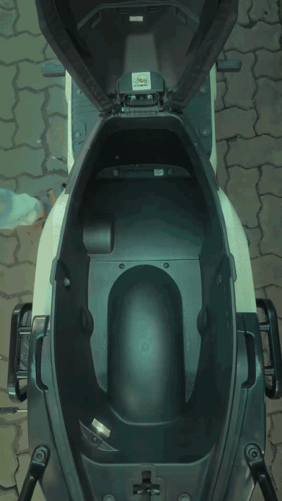 GIF: A man loading bananas into a Winter White Indie's underseat storage, plucking one, and shutting the seat.
