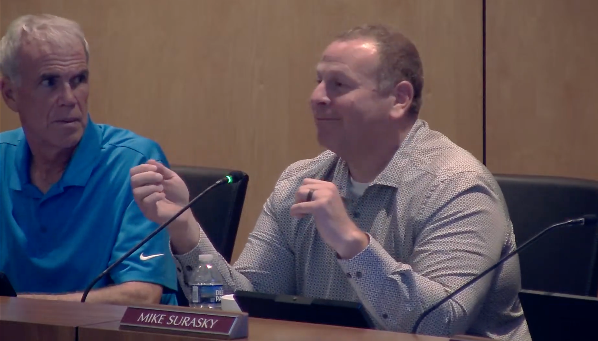 Planning Board member Mike Surasky speaks into a microphone and gestures with both hands during the July 27 meeting while another board member looks toward him.