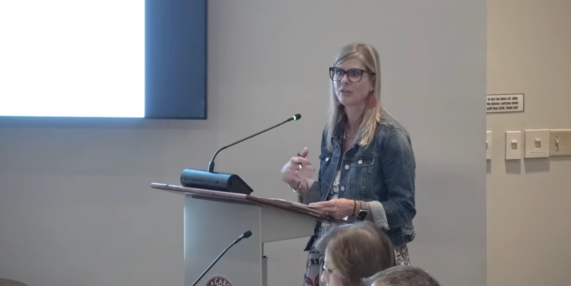 Shannon Poole stands at a lectern in the Clayton Town Council chambers while presenting the downtown parking study findings to council.
