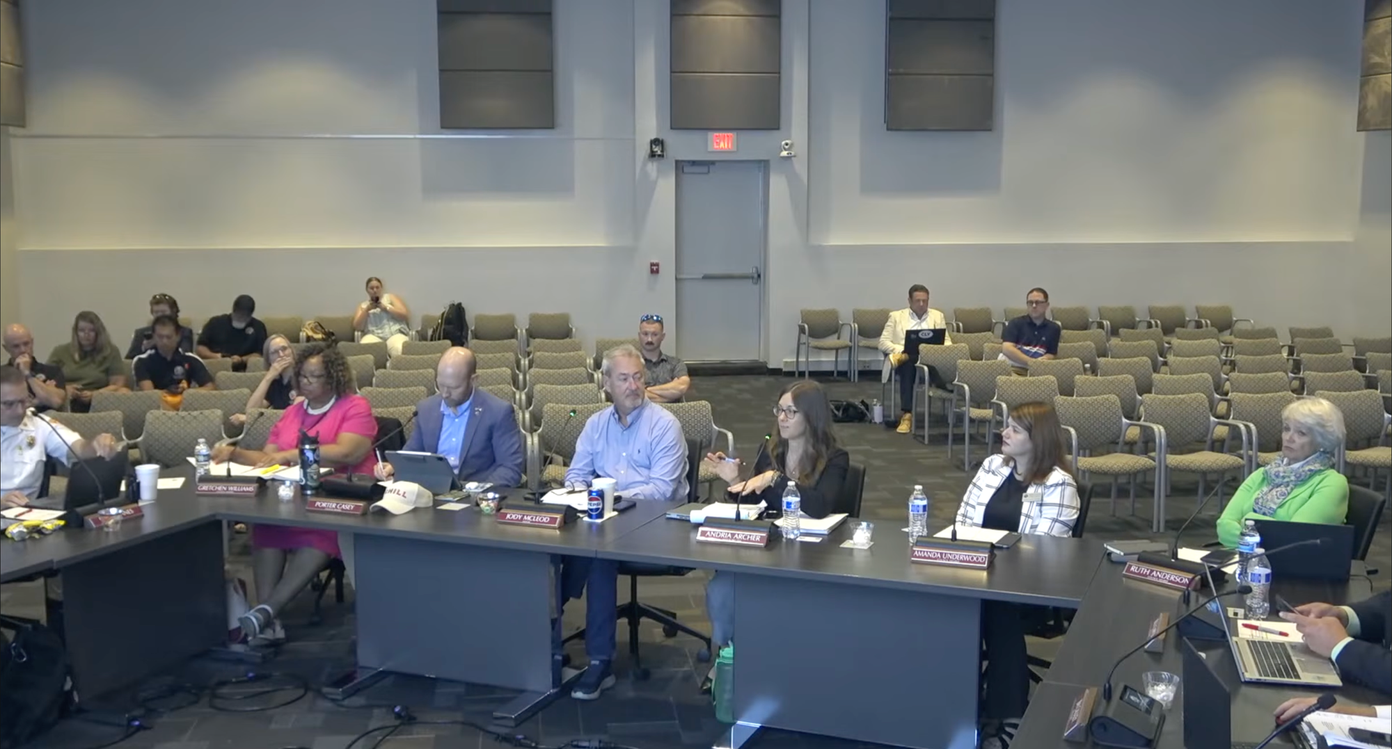 Clayton Town Council members seated around a large meeting table in Council Chambers, with staff and audience members seated behind them.