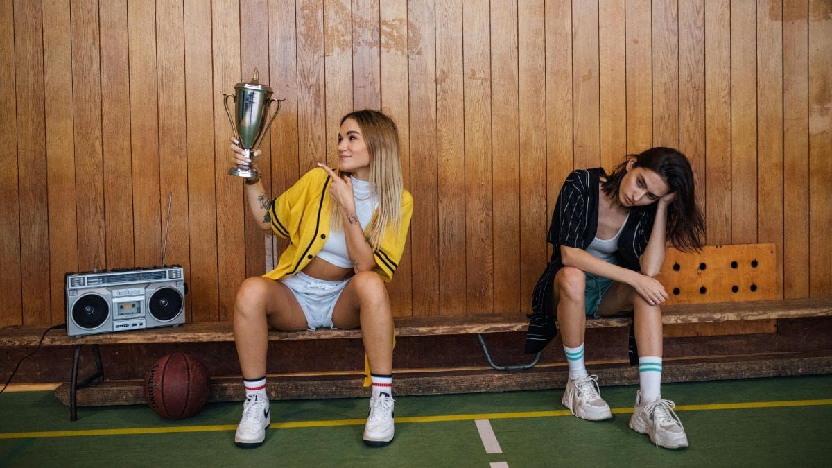 a woman happy with a trophy and another disappointed without it