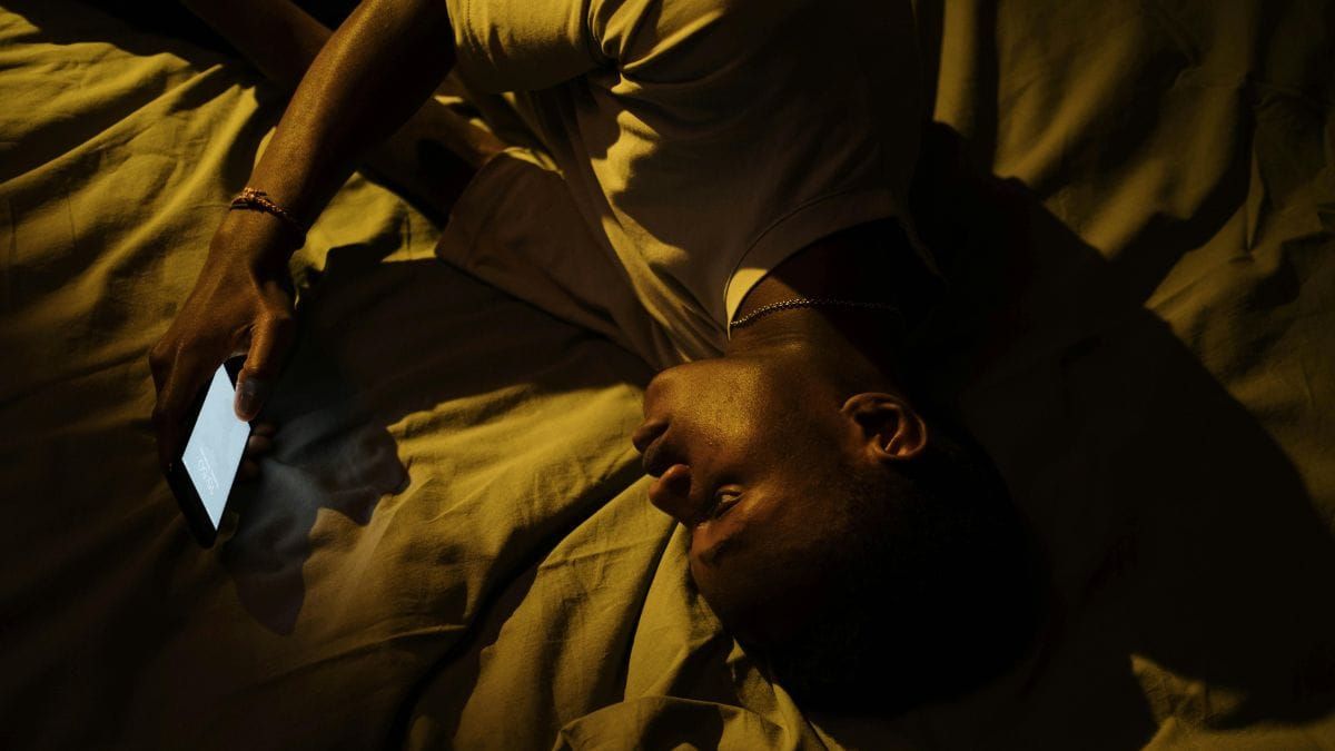 young man lying on bed with phone