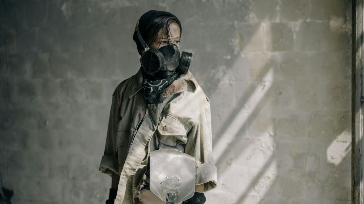 a boy in a large gas mask and leather jacket looking into the distance