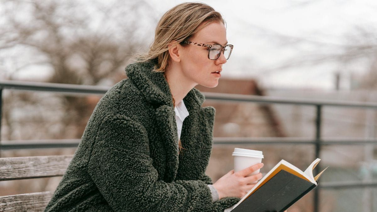 fascinated woman reading a book on a park bench