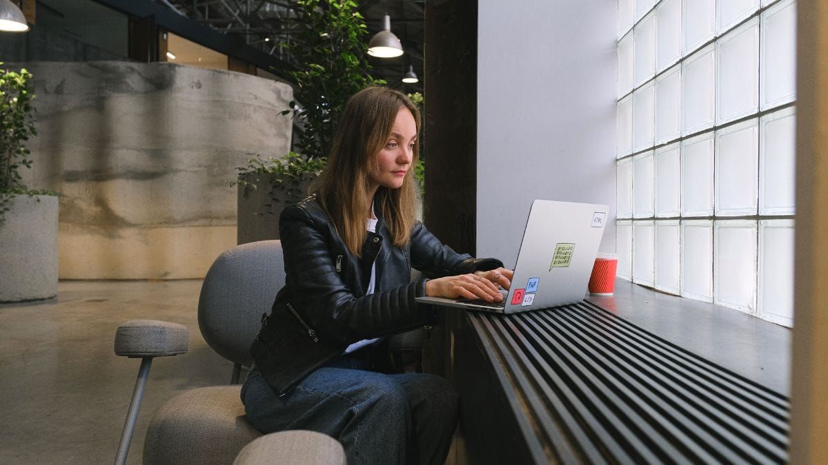A woman working on a laptop in a modern indoor space.