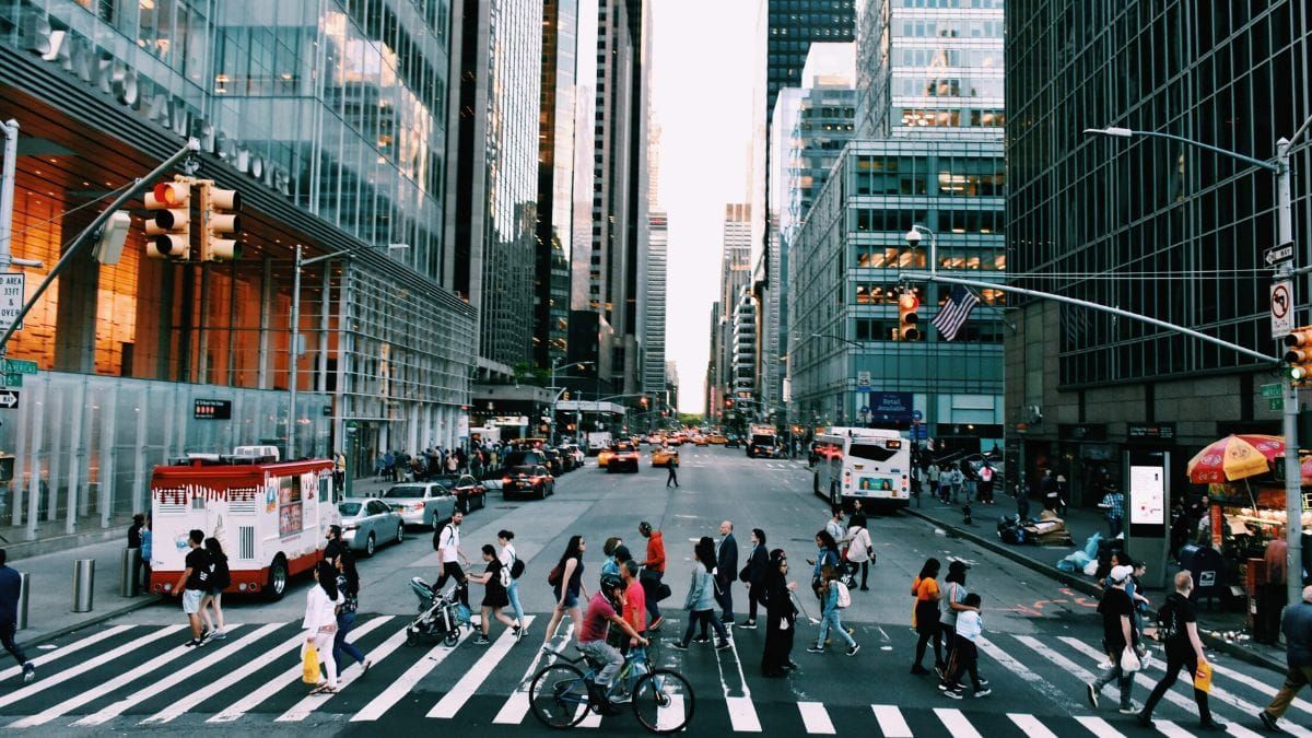People crossing a busy city intersection between office buildings