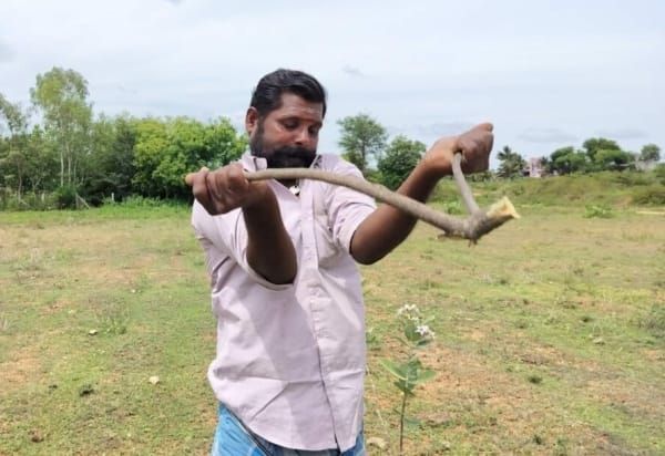 Shanmugan tries to control a quaking branch. The diviner acts as the conductor between the ground and the instrument, he says. Image by Simrin Sirur/Mongabay.