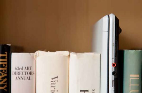 Books spines and a laptop lined up on a shelf