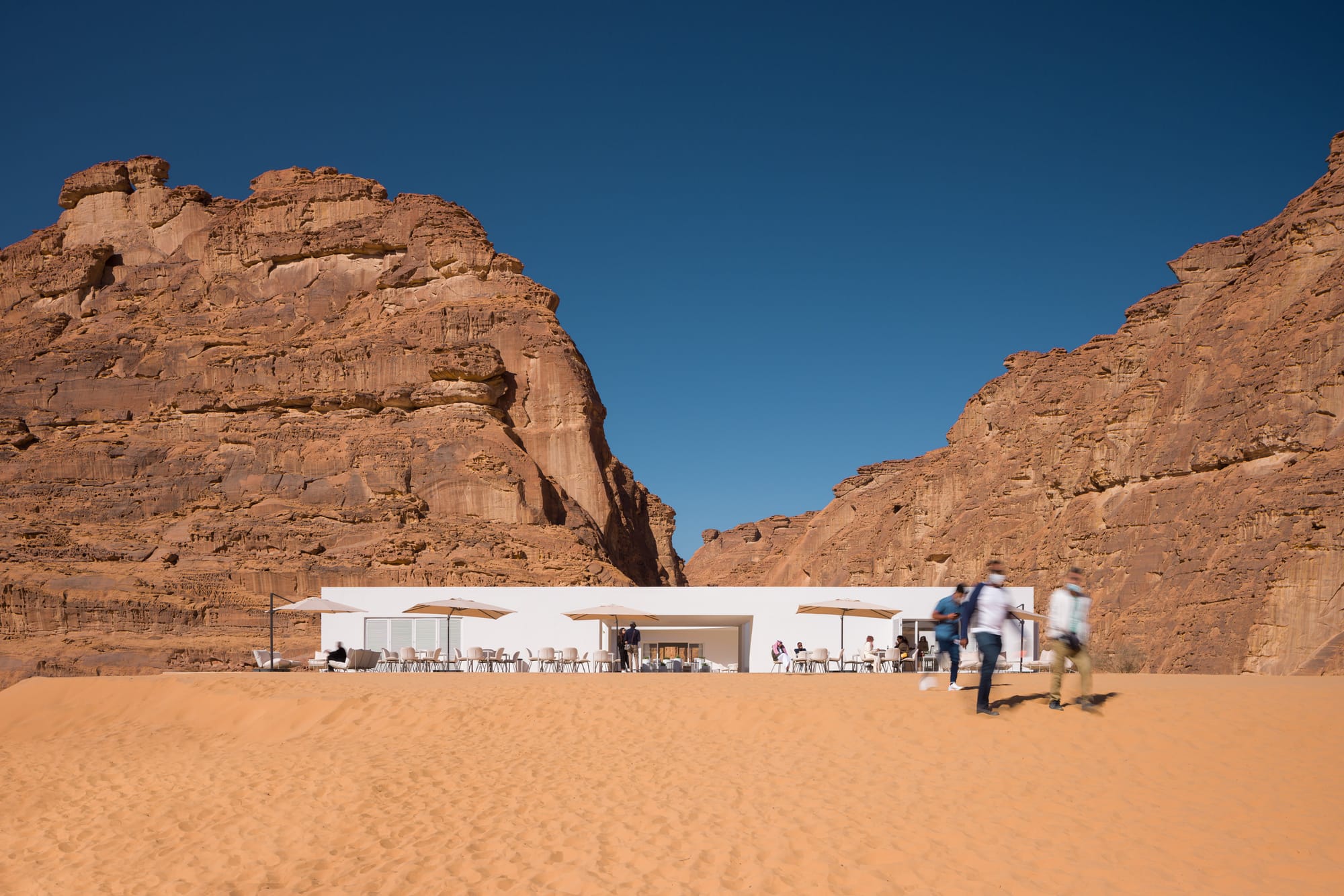 Visitors walking out of the 2022 Desert X visitor center into a vast desert scene