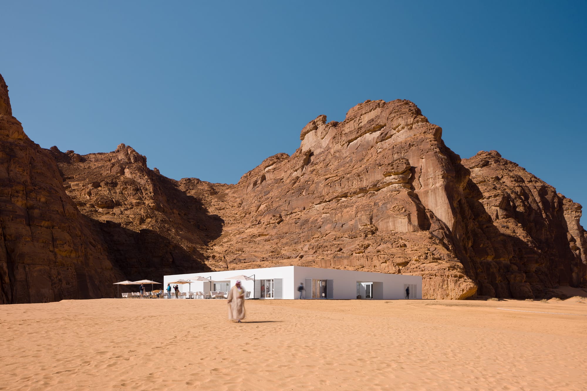 A visitor walking out of the 2022 Desert X visitor center into a vast desert scene
