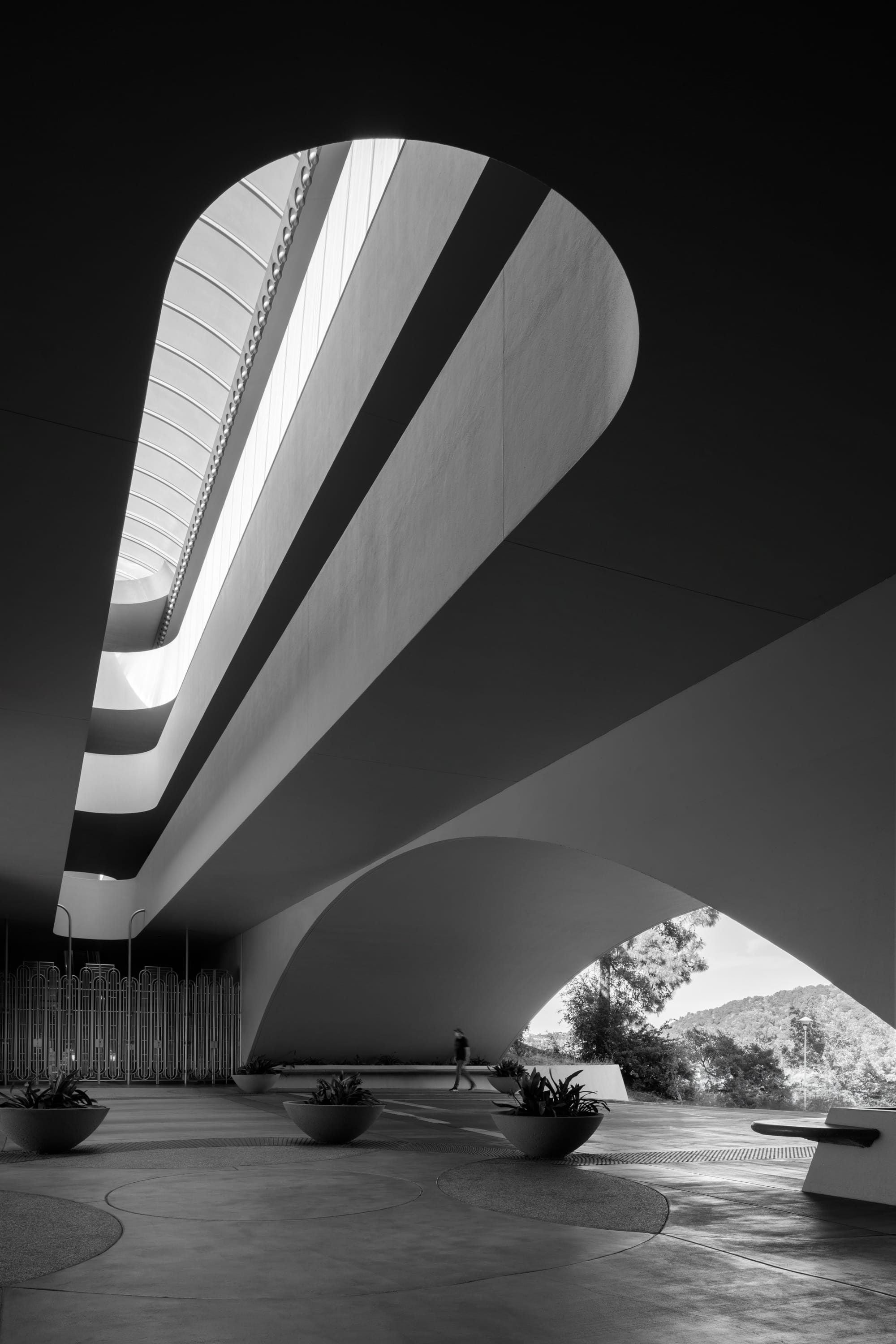 Black and white recreation of a Ezra Stoller photo taken at Marin County Civic Center, by architect Frank Lloyd Wright. It was taken during the covid pandemic and the person is wearing a mask.