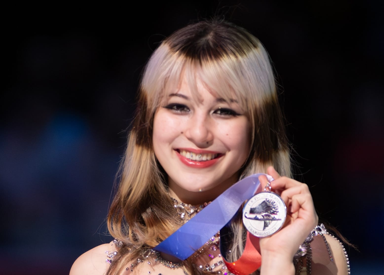a beaming smile on a 20-year old woman holding a silver medal