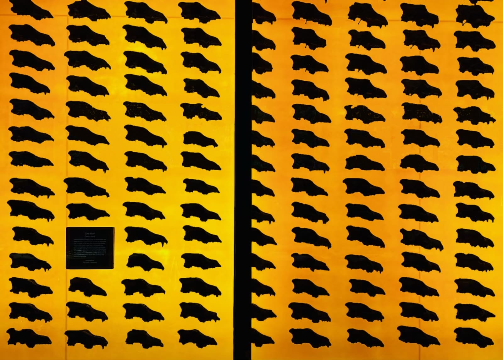 A wall of full of mounted dire wolf skulls, backlit with orange.