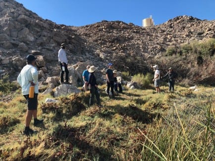 several people standing around along a hillside in a desert