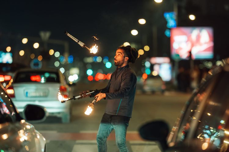 man juggling fire sticks