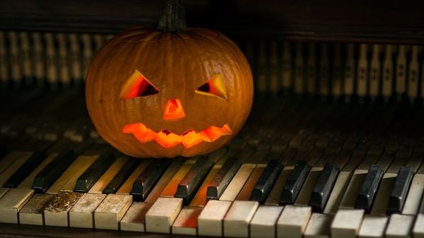 carved halloween pumpkin sitting on piano keys