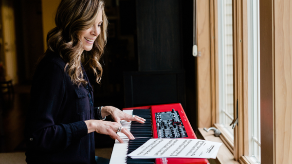 woman playing the piano while looking at sheet music
