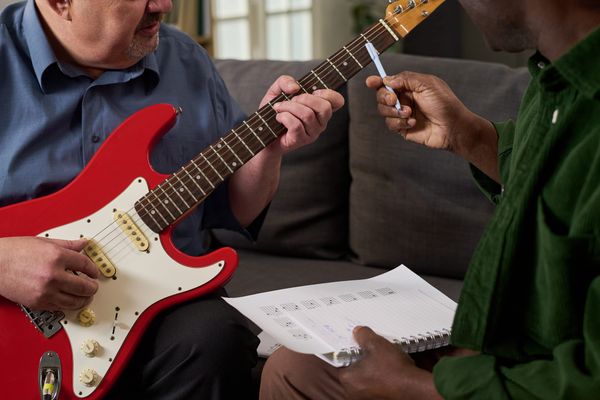 Person learning guitar using printed lead sheet with chords during lesson