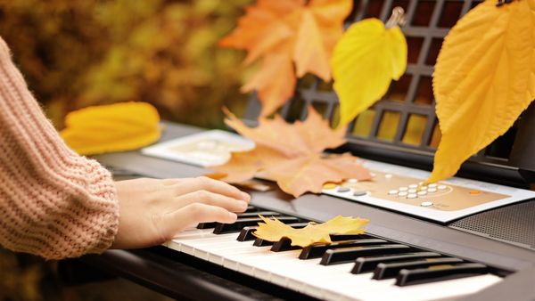 Person playing piano with fall leaves