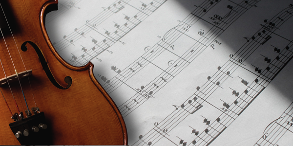 Stringed instrument laying on top of sheet music