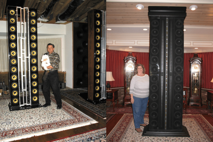 Two different people next to the gargantuan speakers.