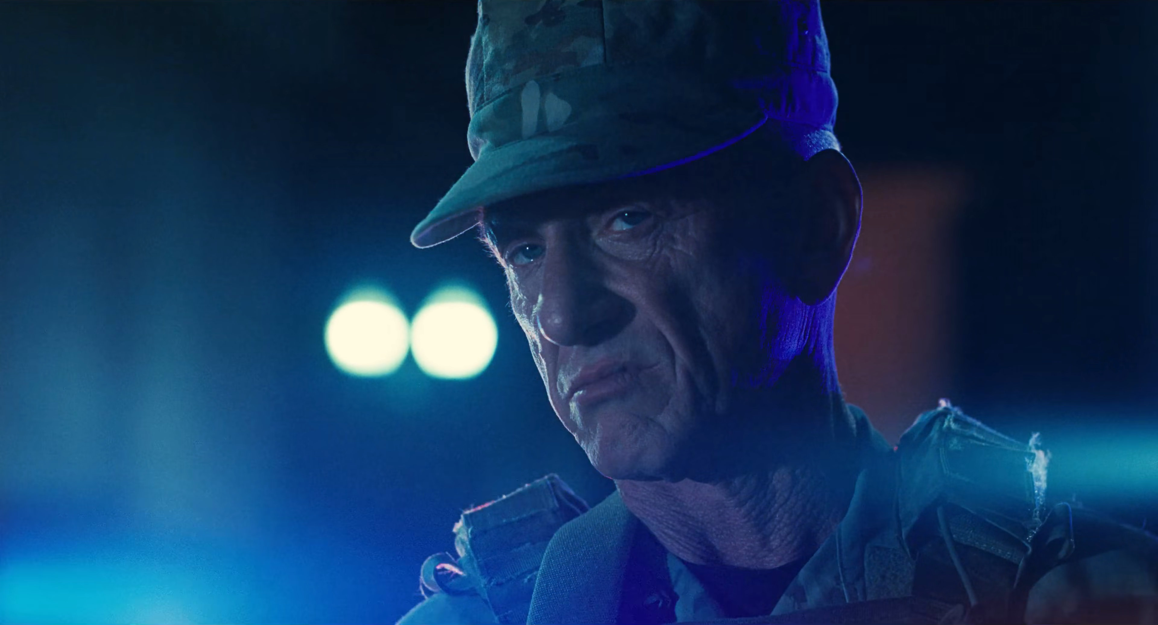 Sean Penn as Lockjaw in One Battle After Another, he's in military fatigues, blue light is around him, he has a weathered, mean look on his face.