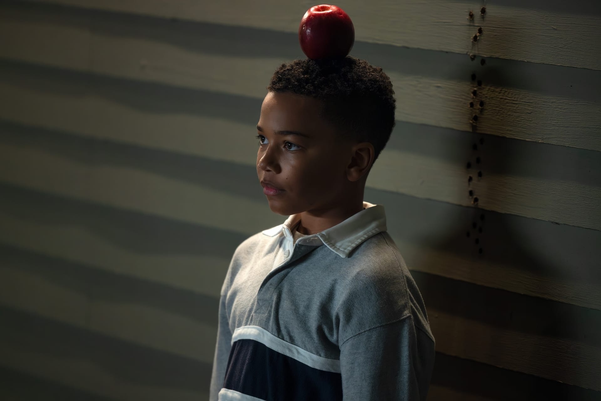 Young John Stewart standing with an apple on his head. 