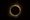 An image of a solar eclipse: a round black moon over a yellow sun, on a black background