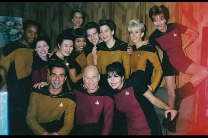 Candid photo from season two of STAR TREK: THE NEXT GENERATION with Patrick Stewart surrounded by the extras in Starfleet uniforms. 