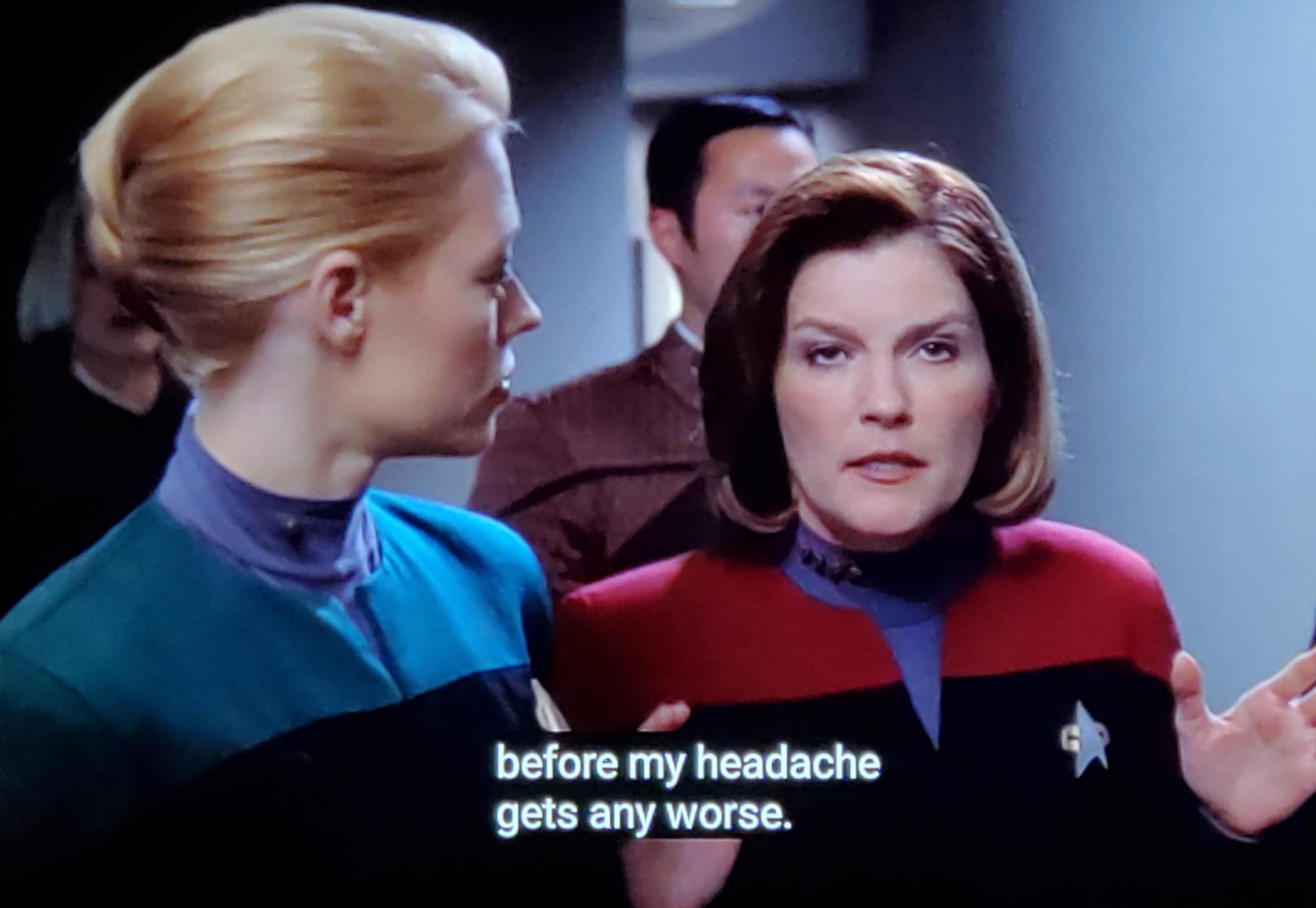 Scene from STAR TREK: VOYAGER where Seven in Starfleet uniform stands next to Captain Janeway, who is rolling her eyes. The caption reads: "... before my headache gets any worse."