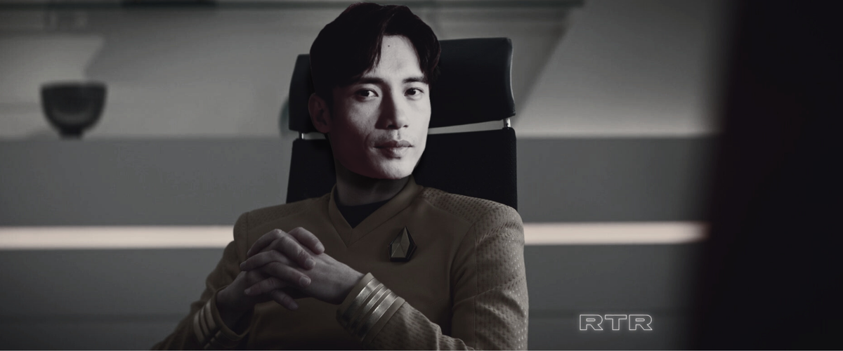 Manny Jancito dreamcast as Tomas R. Cruz, sitting at a desk in a futuristic spaceship office. 