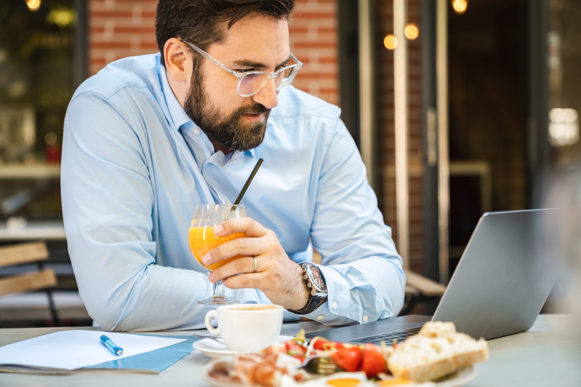 A man sitting on a laptop while enjoying a drink