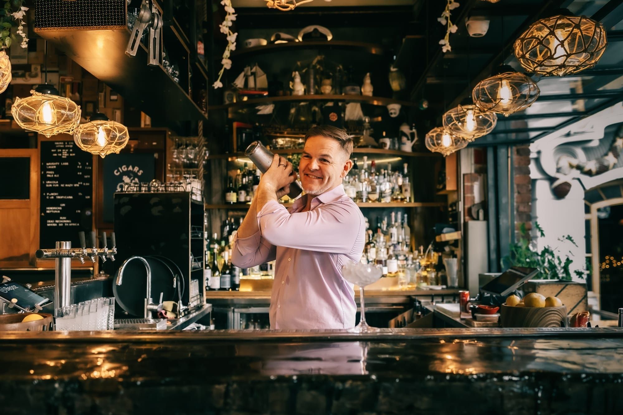 Bar tender shaking the cocktail shaker making a cocktail  