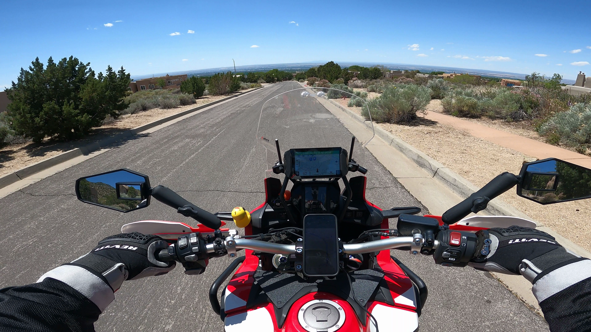 A snapshot from a GoPro recording of me on my motorcycle driving through the neighborhood of the house of Hank Schrader with open views in the distance
