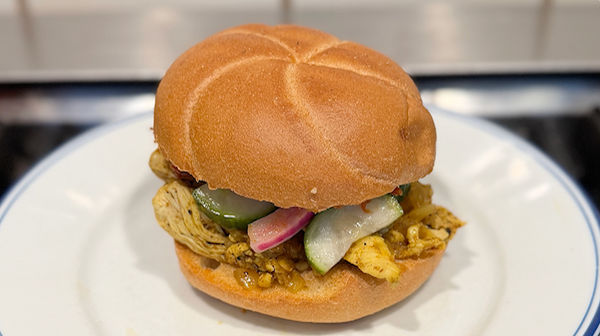 A picture of the Broodje Kerrie Kip sandwich with pickles