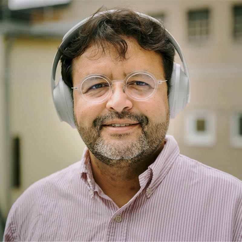 Carlo Carrenho wearing headphones and a red and white striped shirt.